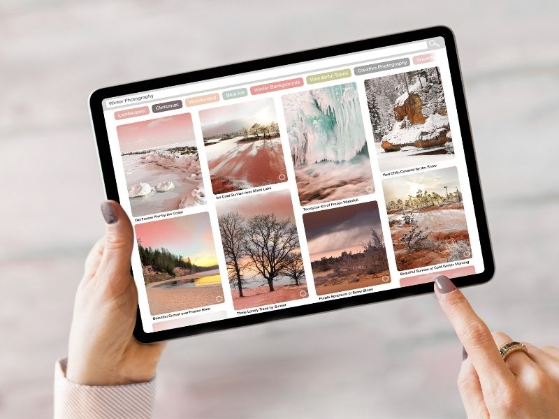Person holding an iPad with the Pinterest app open, displaying a grid of creative pins and inspiration boards.